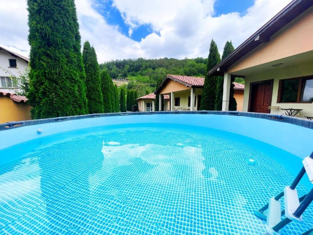a large blue swimming pool in front of a house at Вили Тихия Кът in Ribarica