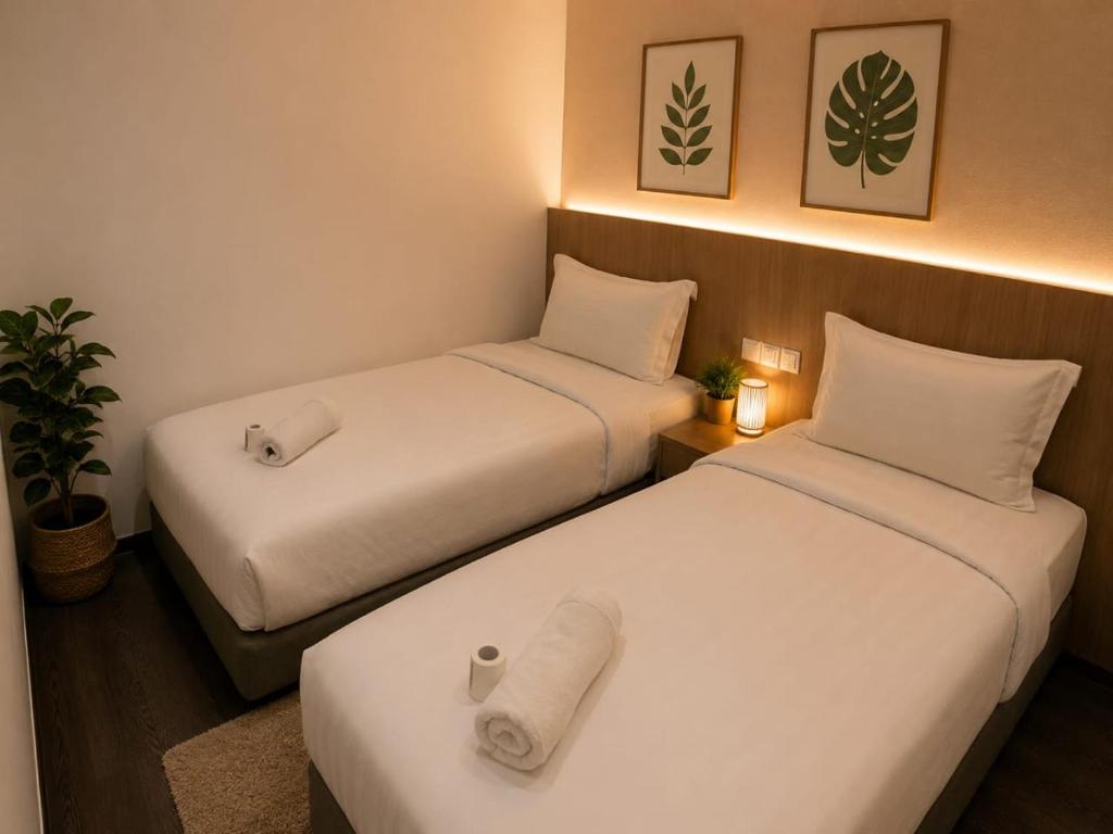 two beds in a hotel room with white sheets at Point Stay GH in Kuching