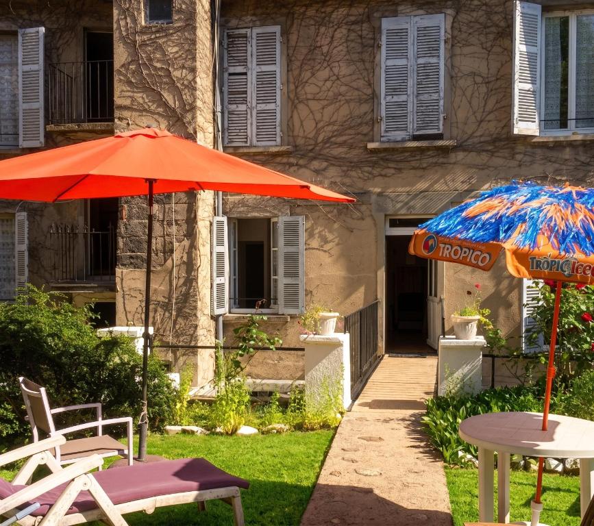 two tables and umbrellas in front of a building at Charmant studio à Néris-les-Bains 20 m² avec jardin privé in Néris-les-Bains