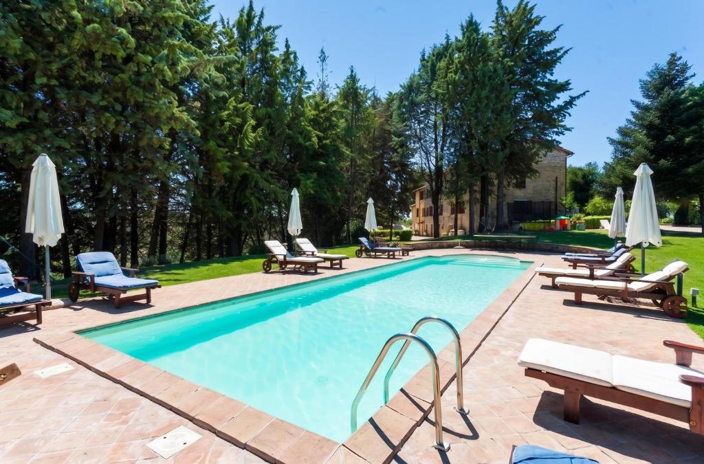 a swimming pool with lounge chairs and umbrellas at Charming house in Ramazzano - Le Pulci with shared pool in Ramazzano