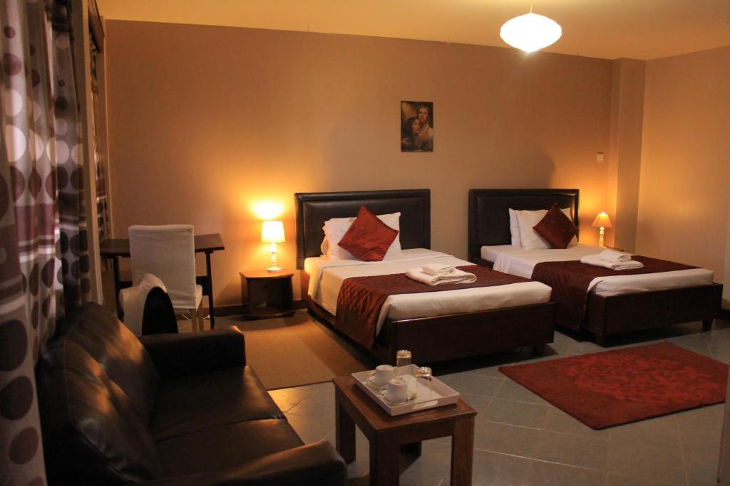 a hotel room with two beds and a couch at Papaya Holiday Home in Kampala