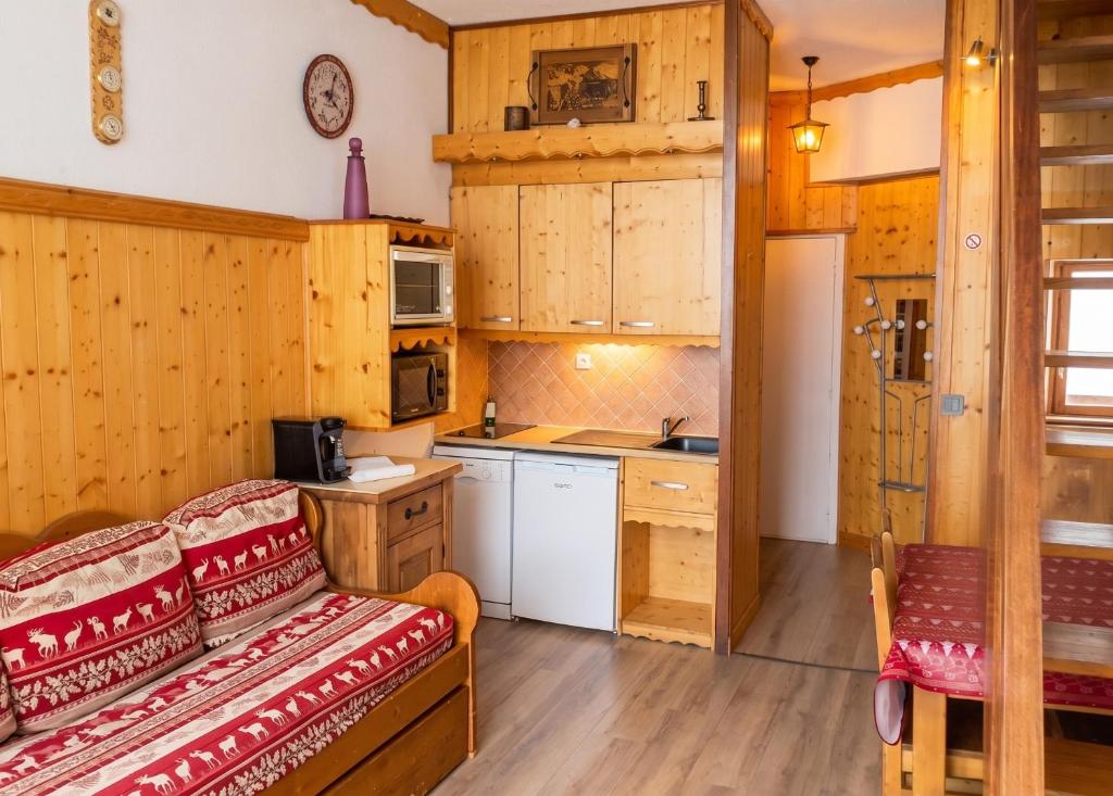 a kitchen with wooden cabinets and a couch in a room at Appartement charmant à Les Menuires, 36 m², vue montagne. in Saint-Martin-de-Belleville