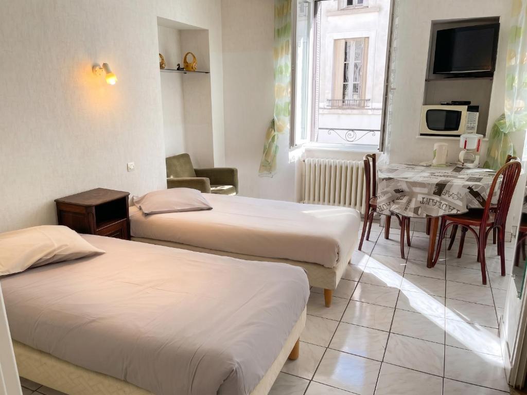 a room with two beds and a table with a dining room at Charmant studio à Néris-les-Bains de 20 m² in Néris-les-Bains