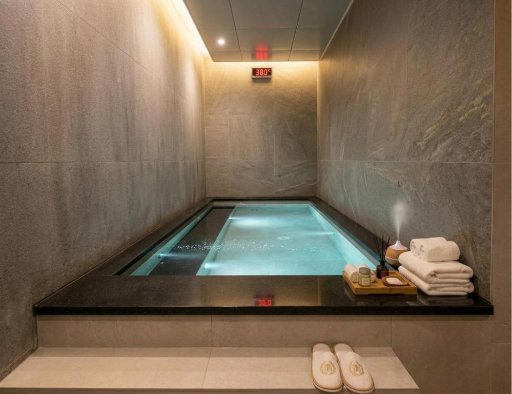 a swimming pool in a bathroom with towels andippers at Haeundae Marine Capsule Hotel&Spa in Busan