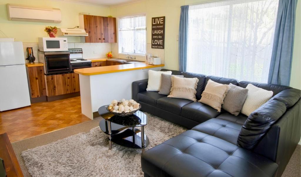 a living room with a couch and a kitchen at Manilla Cottage - Manilla NSW in Manilla