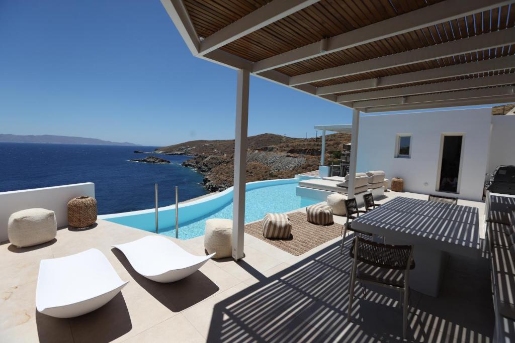 a patio with white chairs and a view of the ocean at Three Drops in Kanala