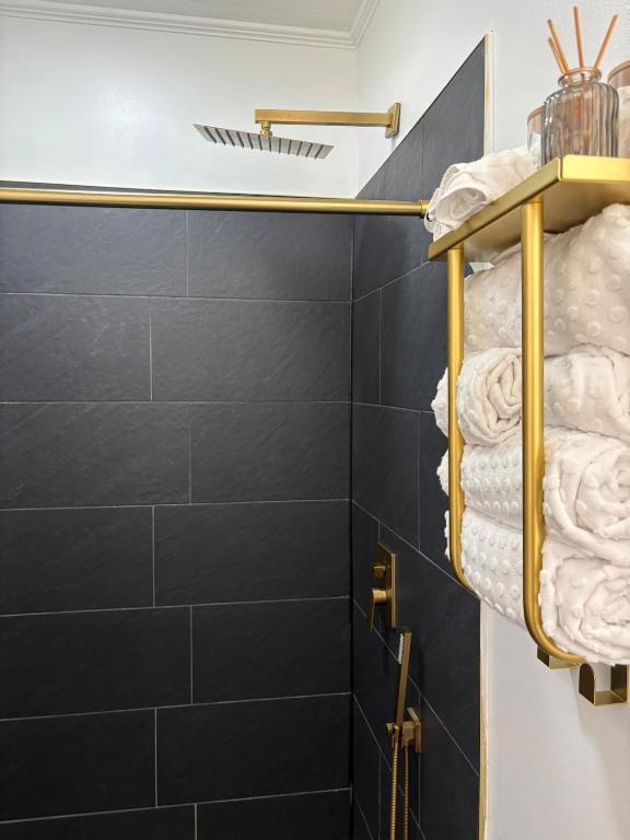 a bathroom with black tiled walls and gold towel racks at Tranquil Suite Studio in Wilson