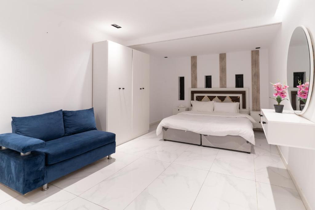 a white bedroom with a bed and a blue couch at Jeddah Apartment in Jeddah