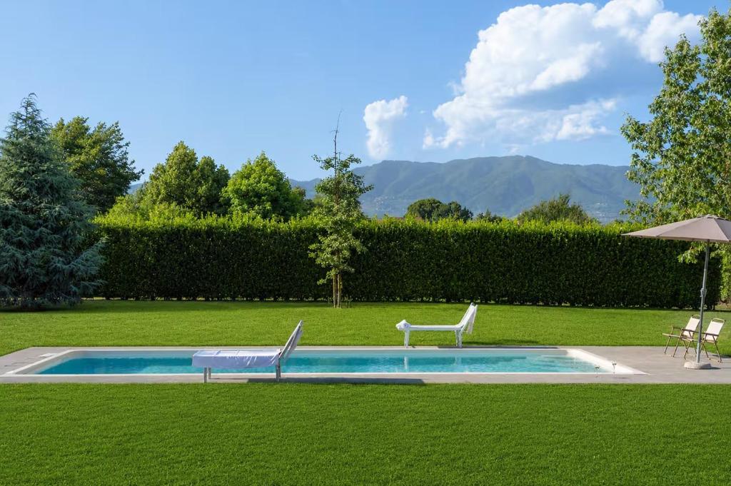 a swimming pool with two chairs and an umbrella at Villa Angela in Capannori