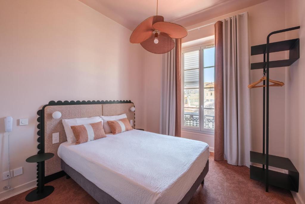 a bedroom with a bed and a window at Hotel Louvia in Menton