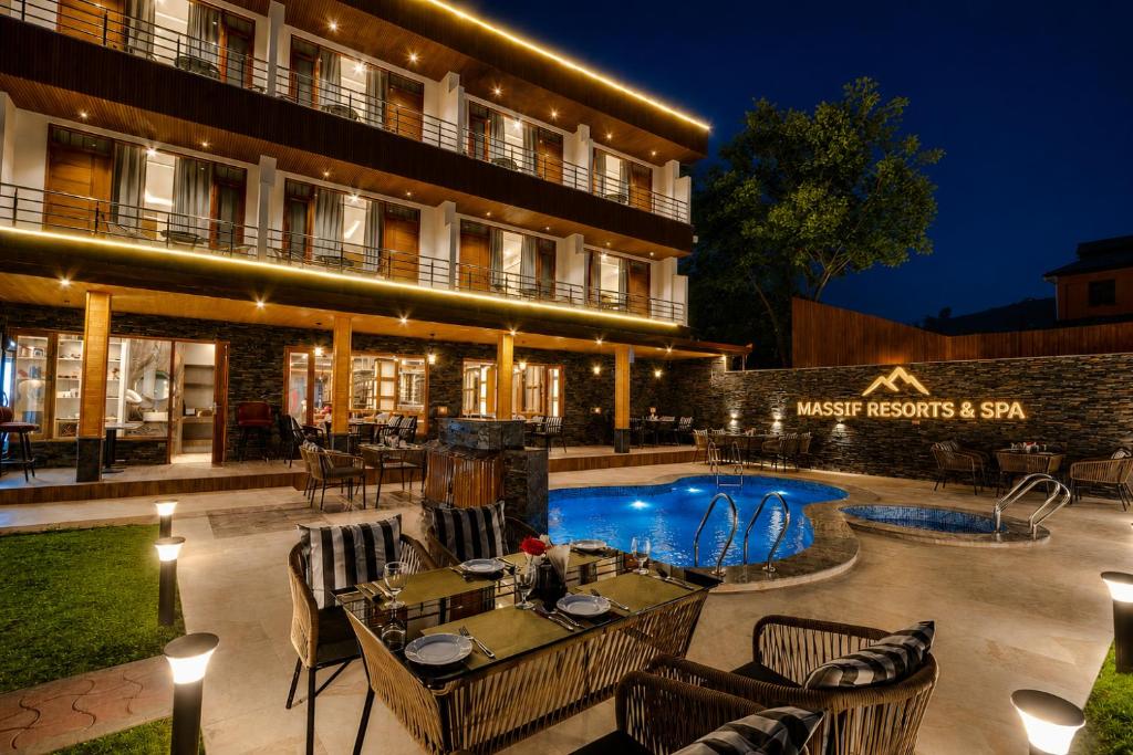 a hotel with a restaurant and a swimming pool at night at Massif Resort & Spa, Manali in Manāli