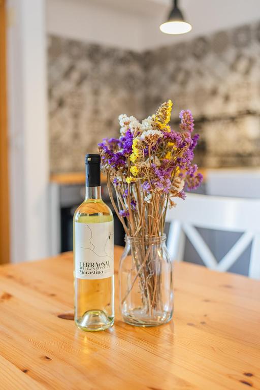 a bottle of wine sitting next to a vase of flowers at Apartments TERRAeSAL in Zadar