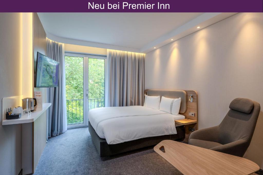 a hotel room with a bed and a chair at Premier Inn Göttingen in Göttingen