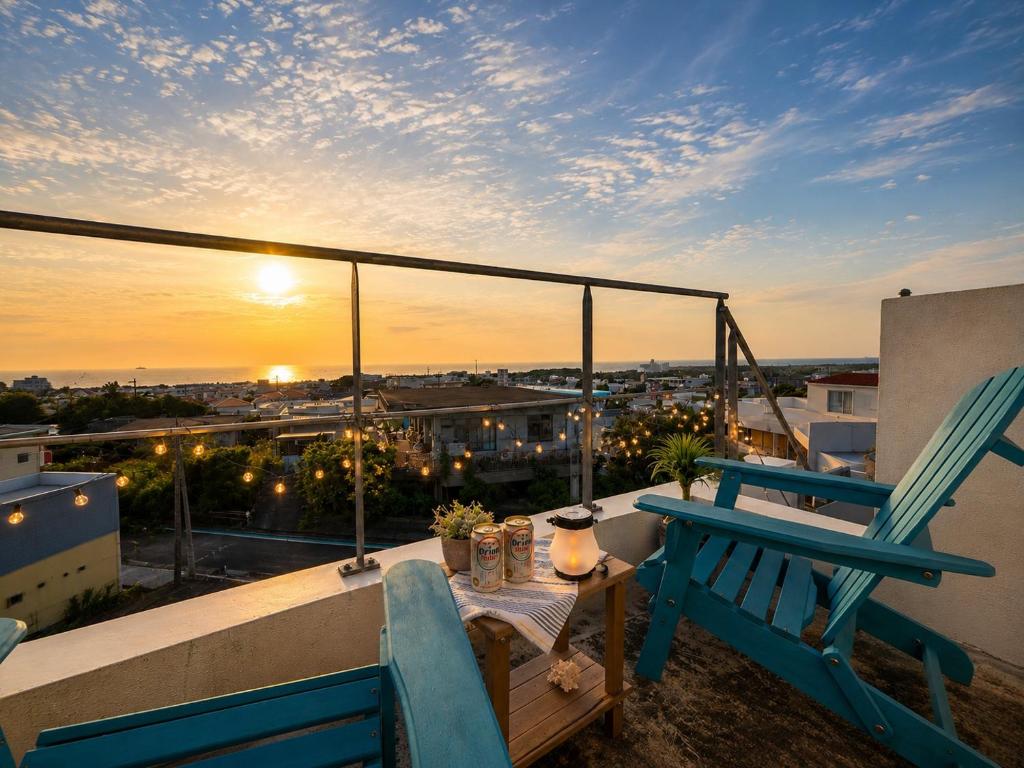 a balcony with a table and a chair and the sunset at Balmy Ocean OKINAWA in Yomitan