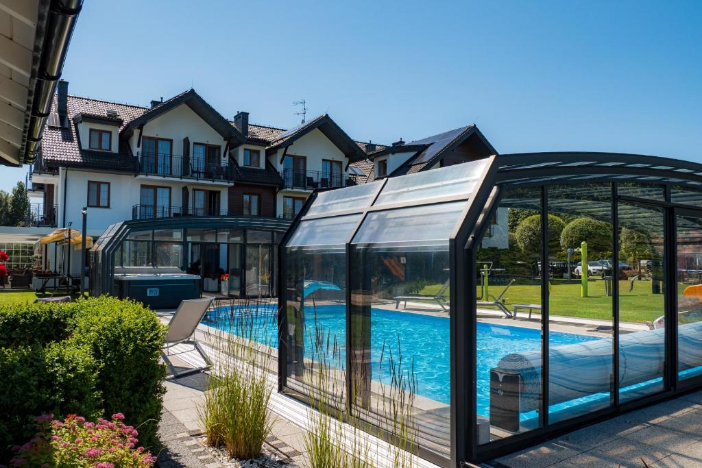 a glass house with a swimming pool in a yard at Perla Mare Apartamenty in Krynica Morska