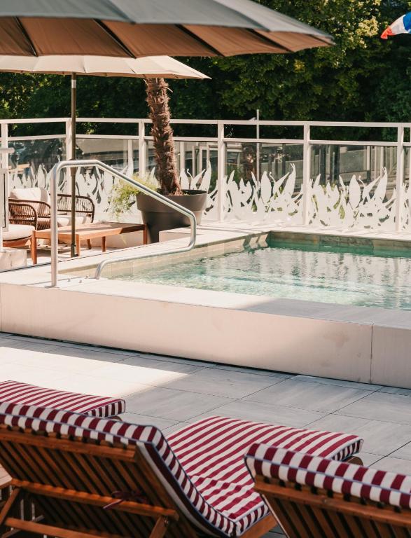 a swimming pool with chairs and an umbrella at Le Riviera - Hôtel Restaurant & Spa - Ex Golden Tulip Aix les bains in Aix-les-Bains