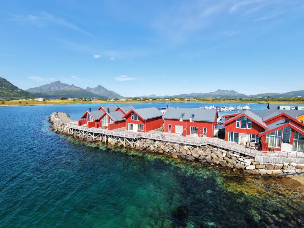 a row of red houses on a dock in the water at Modern seafront cabin with sauna 8 mins to Leknes in Storeidet