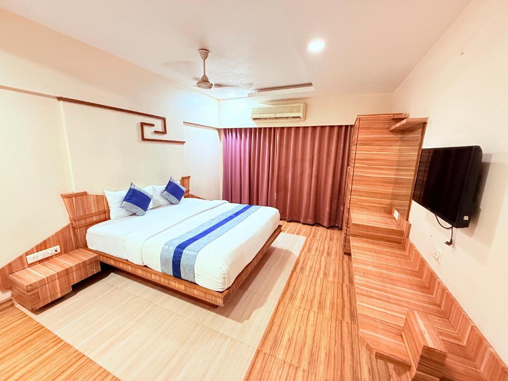 a bedroom with a bed and a flat screen tv at Hotel Praveen International in Ulhāsnagar