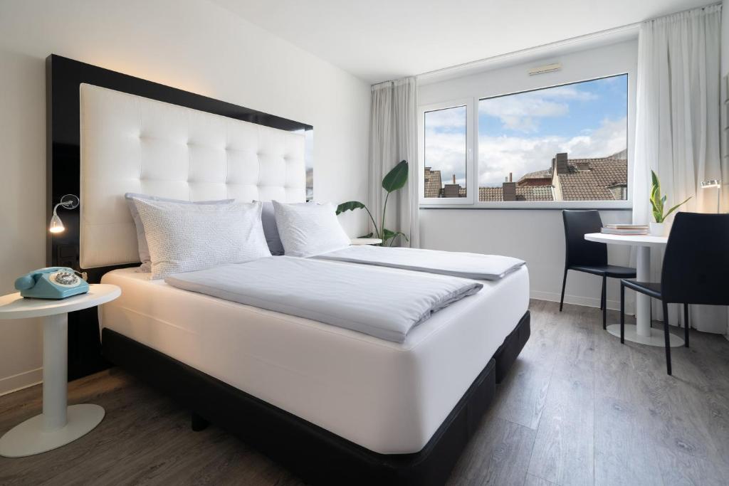 a bedroom with a large white bed and a table at INNSiDE by Meliá Aachen in Aachen