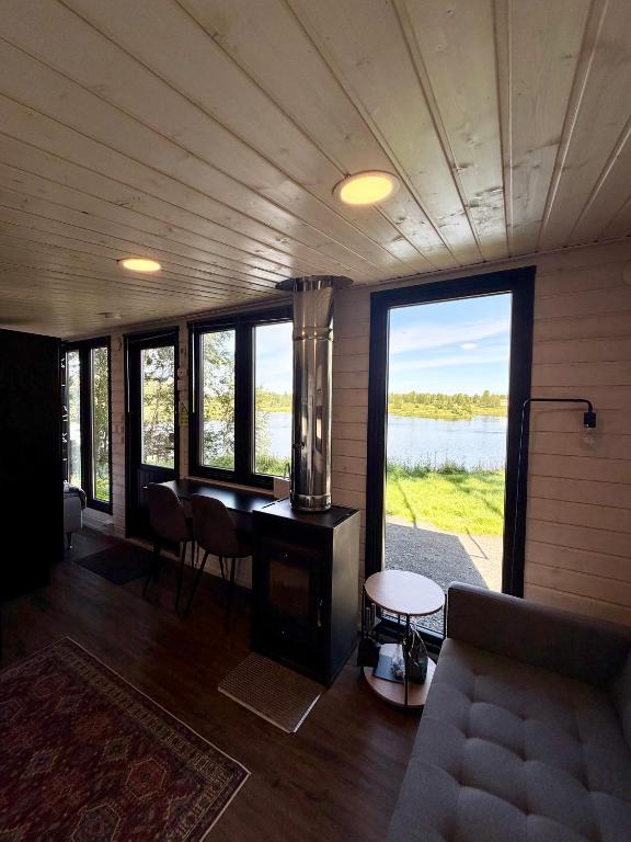 a living room with a table and a view of a lake at Aurora Forest Cabin in Rovaniemi