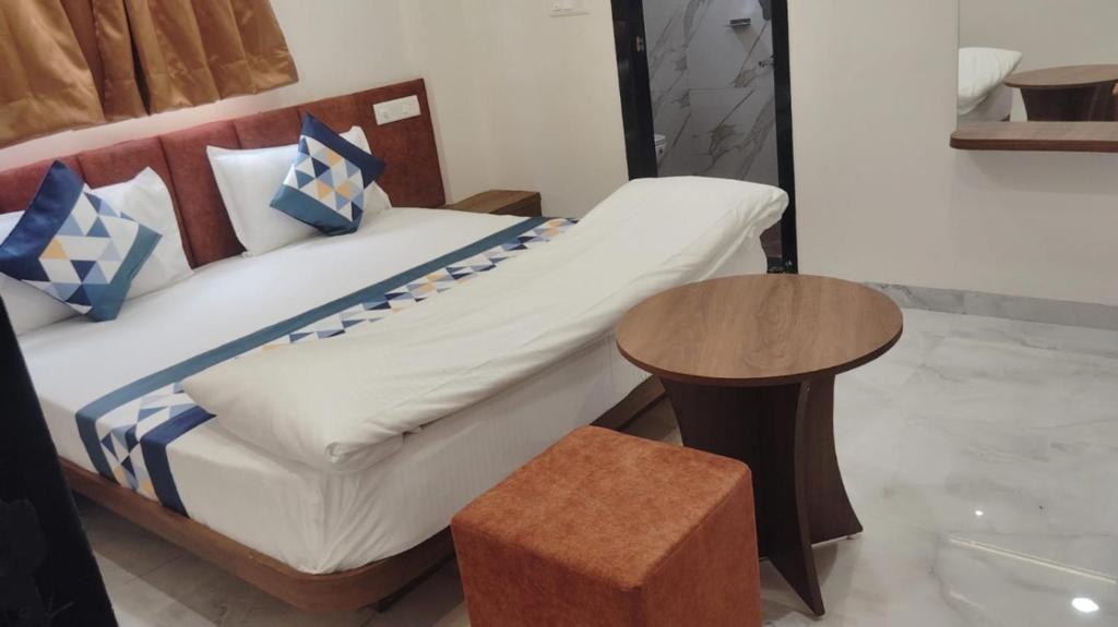 a bed with blue and white pillows and a table at Hotel G17 Dhamnod in Dhāmnod