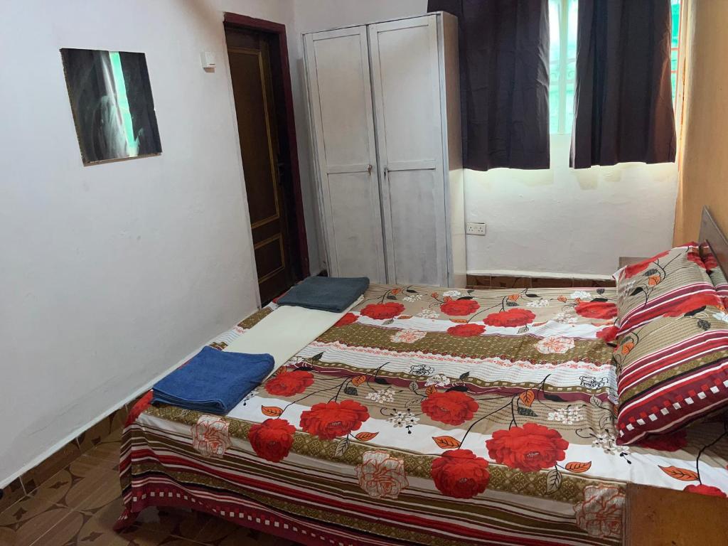 a bed with red flowers on it in a room at Sumanya guest house 3 in Sukuta