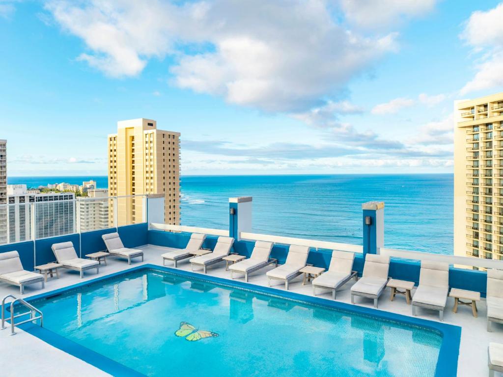 a swimming pool on the roof of a building with the ocean at Pacific Monarch Hotel in Honolulu
