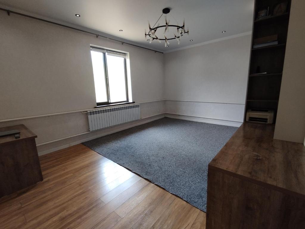 an empty room with a chandelier and a window at Aziz House in Naryn
