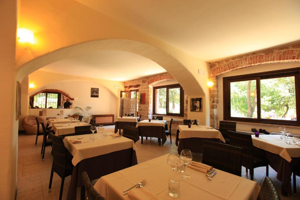 a restaurant with white tables and chairs and windows at Nascar Hotel in Santa Maria Navarrese