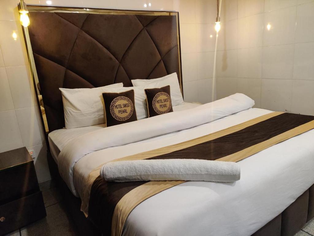 a bedroom with a large bed with two pillows at Swiss Pearl Hotel Lahore in Lahore