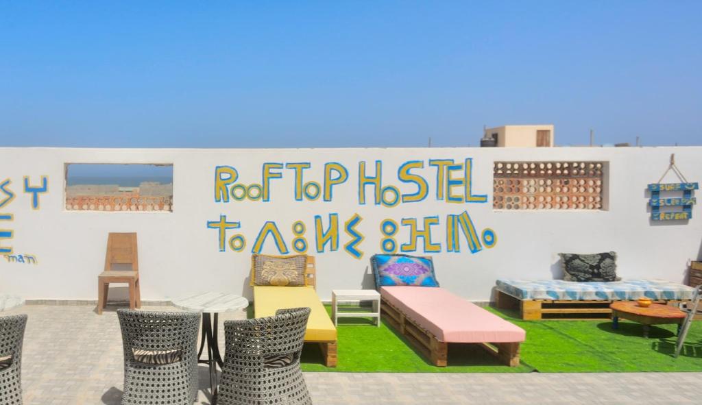 a room with chairs and a wall with a sign at Rooftop Hostel Dakhla in Dakhla