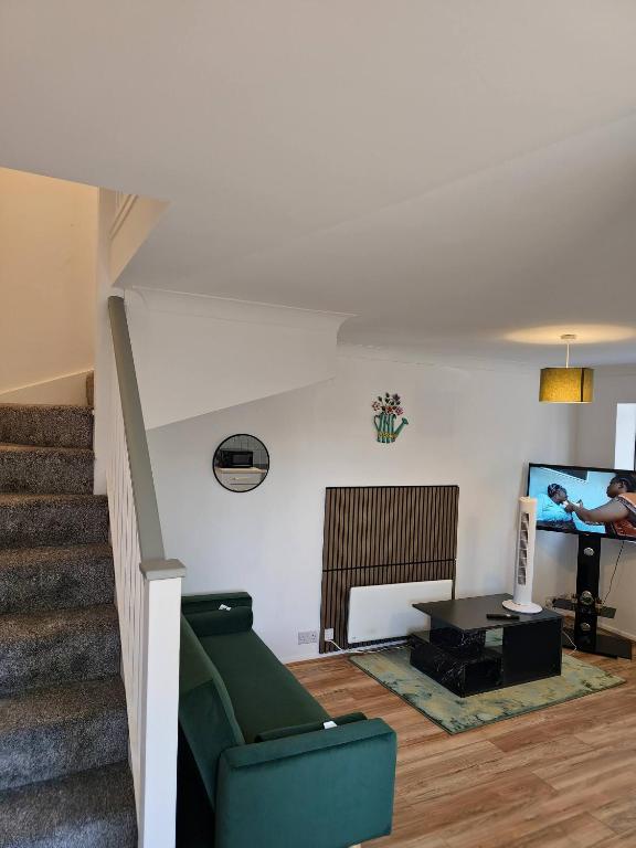 a living room with a green couch and a television at The Chilux stylish apartment in Rainham