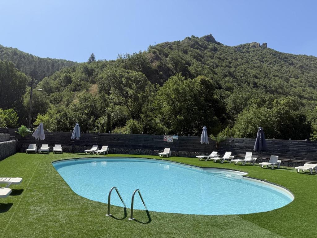 a swimming pool with chairs and a mountain in the background at Camping du Bourg in Digne-les-Bains
