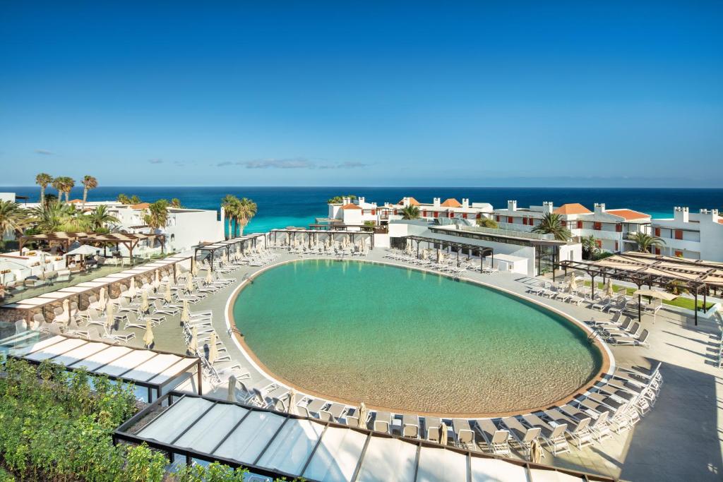 a swimming pool with lounge chairs and the ocean at Esencia de Fuerteventura by Princess in Playa Jandia