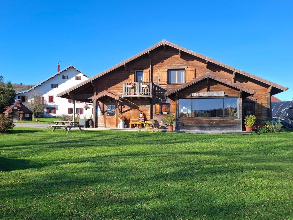 a log cabin with a large grass field at Les Bruchels in Longechaux