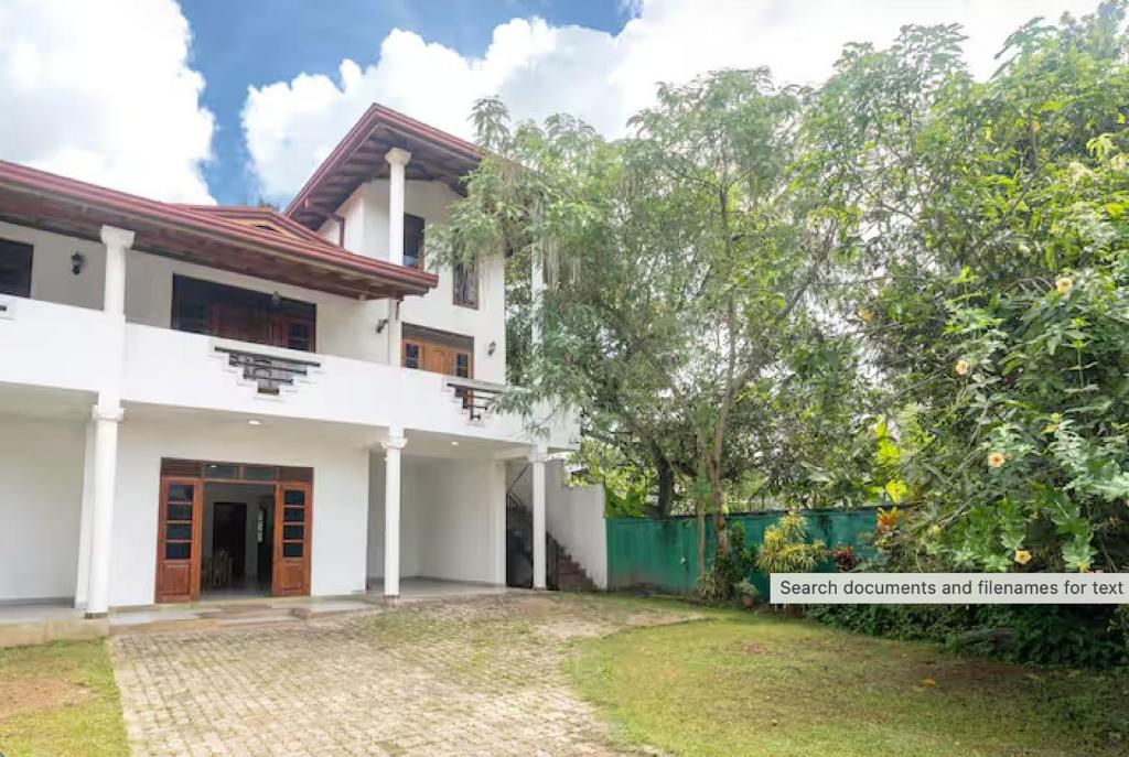a white house with a tree in front of it at The Ivy Grove in Mahabage