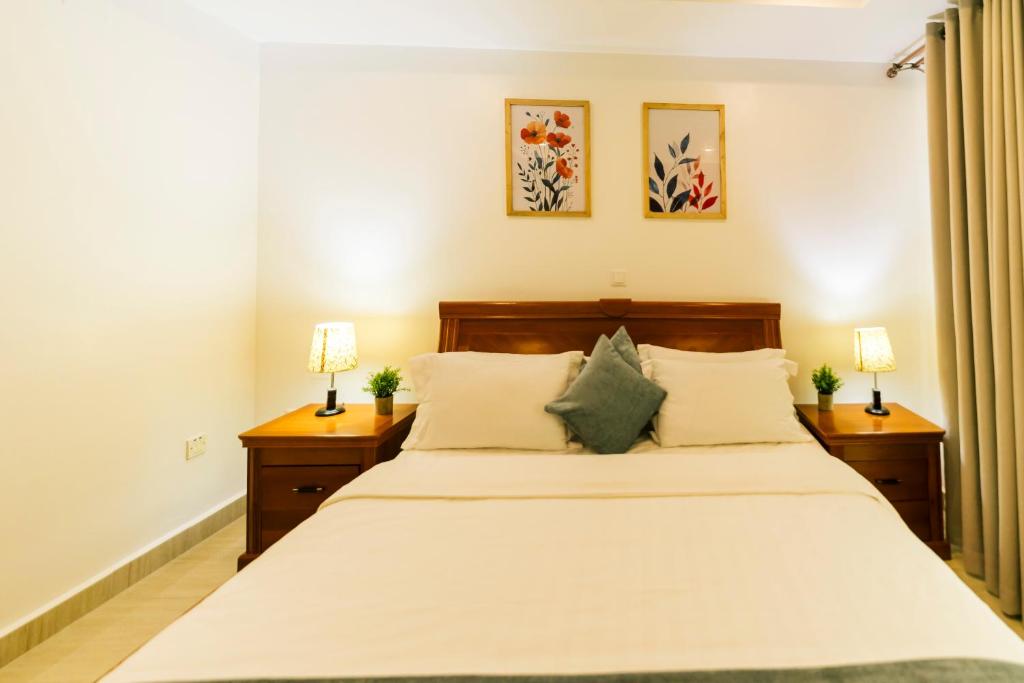 a bedroom with a large bed with two night stands at Highlands Suites Hotel and Apartments in Kigali