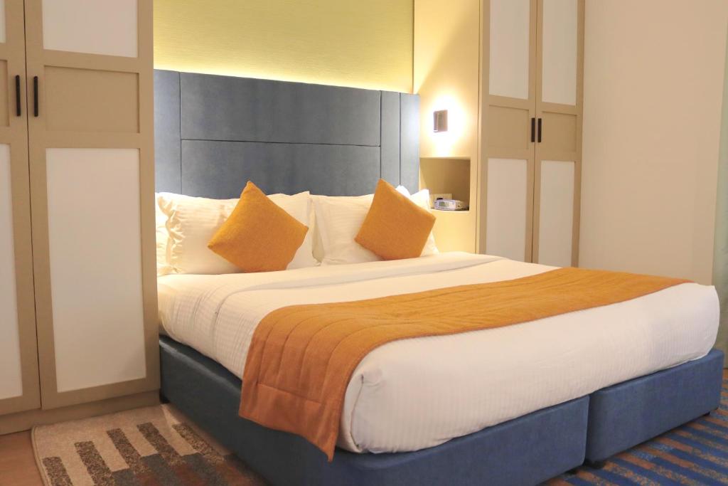 a bedroom with a large bed with orange pillows at The Eclipse Boutique Suites in Abu Dhabi