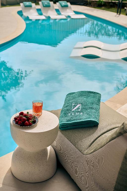 a drink and fruit on a table next to a swimming pool at Zeus Piraeus Grand in Piraeus