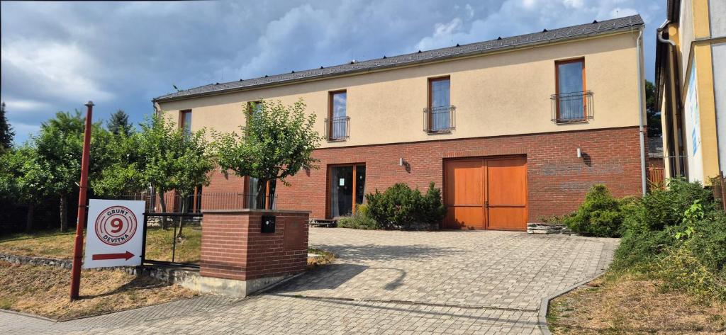 a brick building with a orange door and a sign at Grunt Devítka in Hvozd