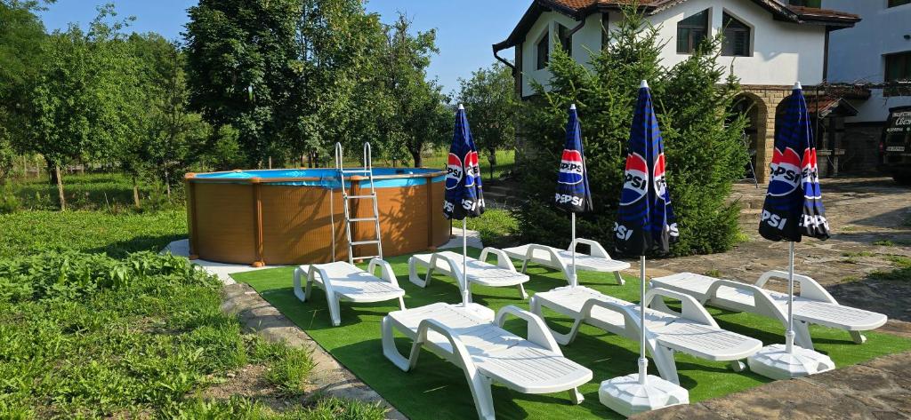 a group of lawn chairs and a pool with flags at Къща за гости ЧЕРИ in Tryavna
