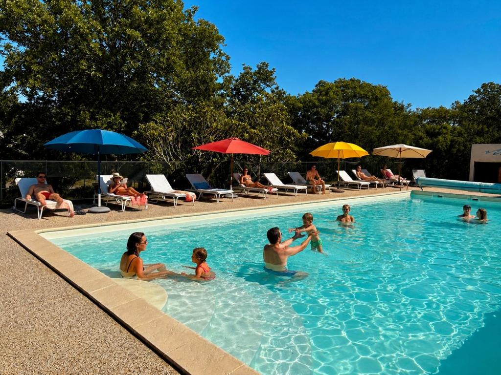 a group of people sitting in a swimming pool at Hôtel Les Persèdes in Lavilledieu