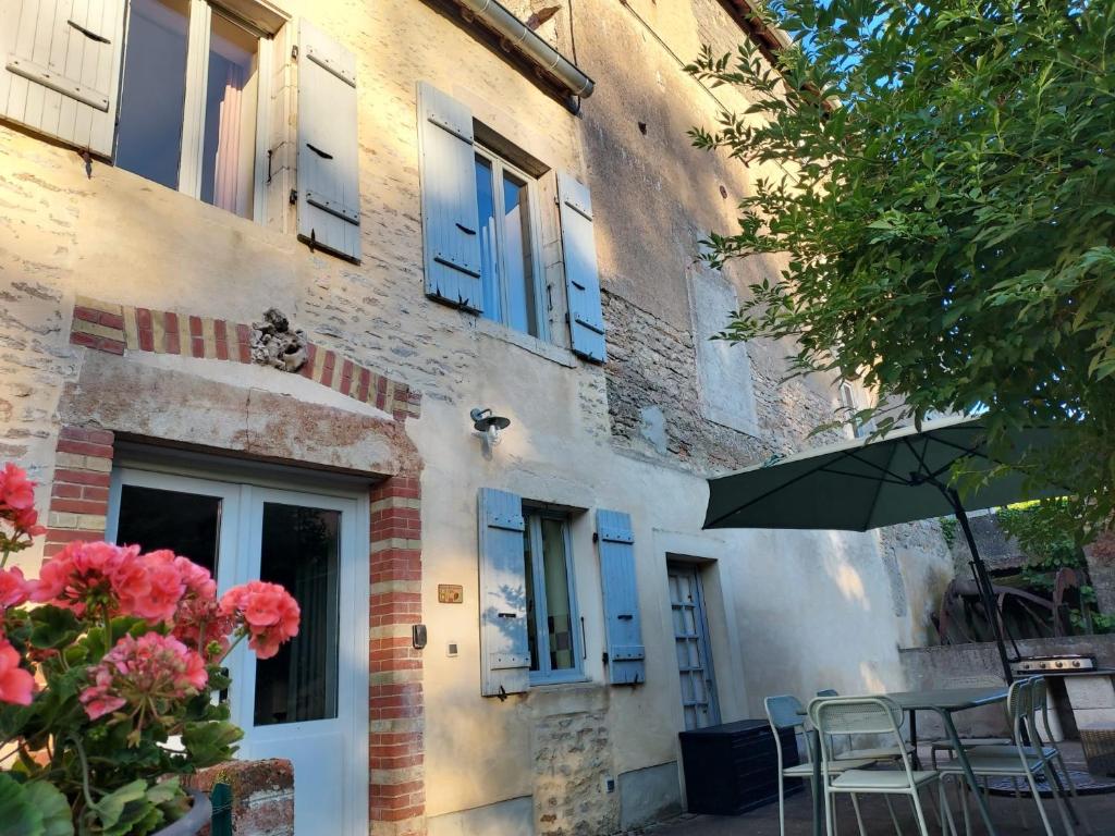 a building with blue windows and a table and chairs at Le Liboureau in Saint-Jean-de-Vaux
