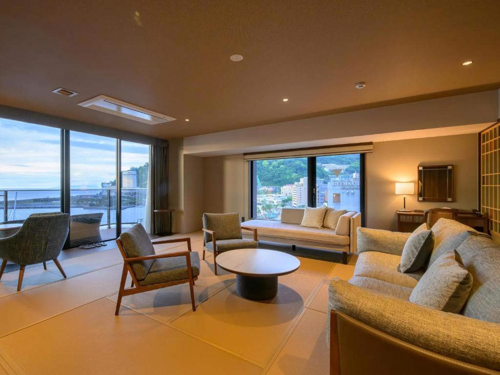 a living room with a couch and chairs and windows at Atami Hotel Nagisakan in Atami
