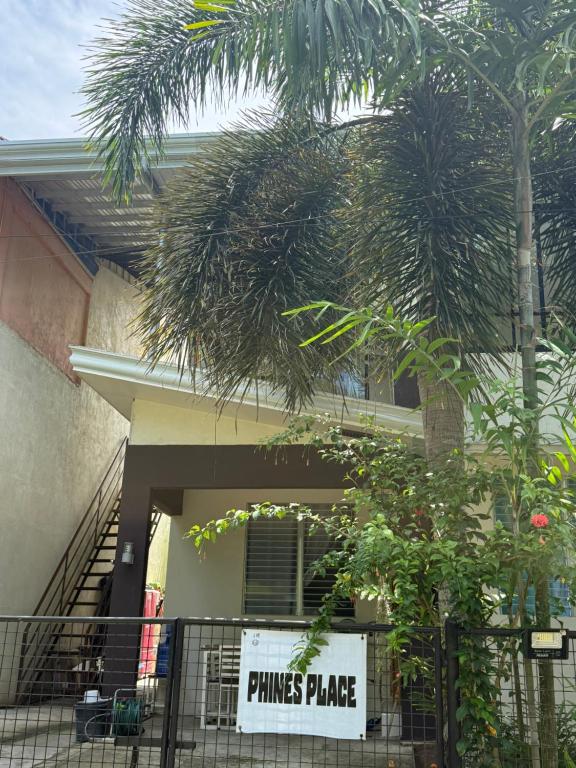 Eine Palme vor einem Gebäude mit einem Schild in der Unterkunft Phines Place in Panglao