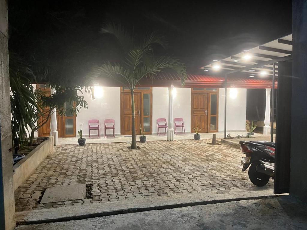 a building with chairs and a palm tree in front of it at Yala Villa Harmony in Debarawewa