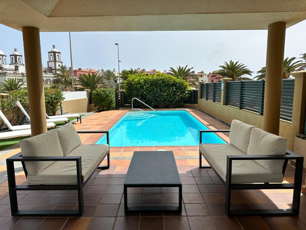 a patio with a pool and two chairs and a table at Villa Meloneras in Meloneras