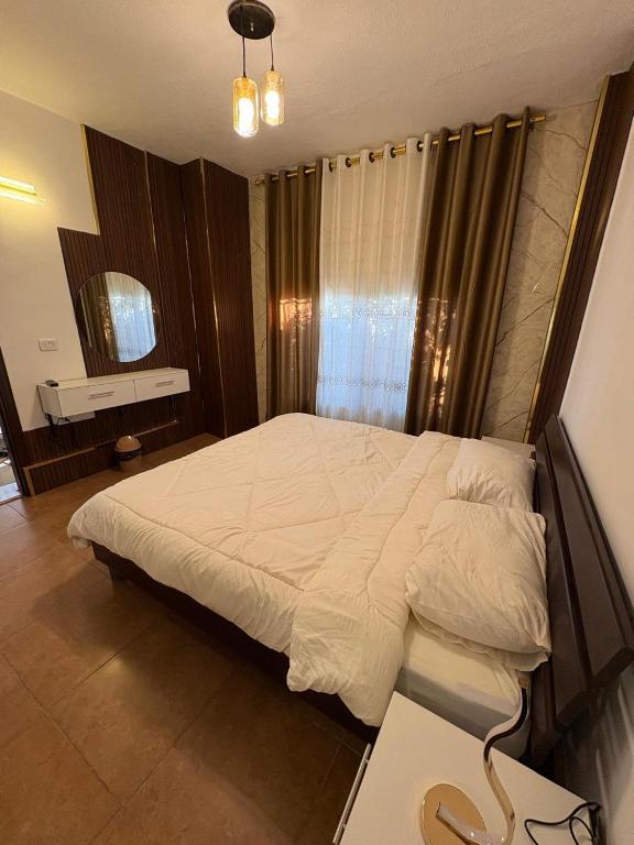 a bedroom with a large white bed with a window at Cozy farm in Jerash