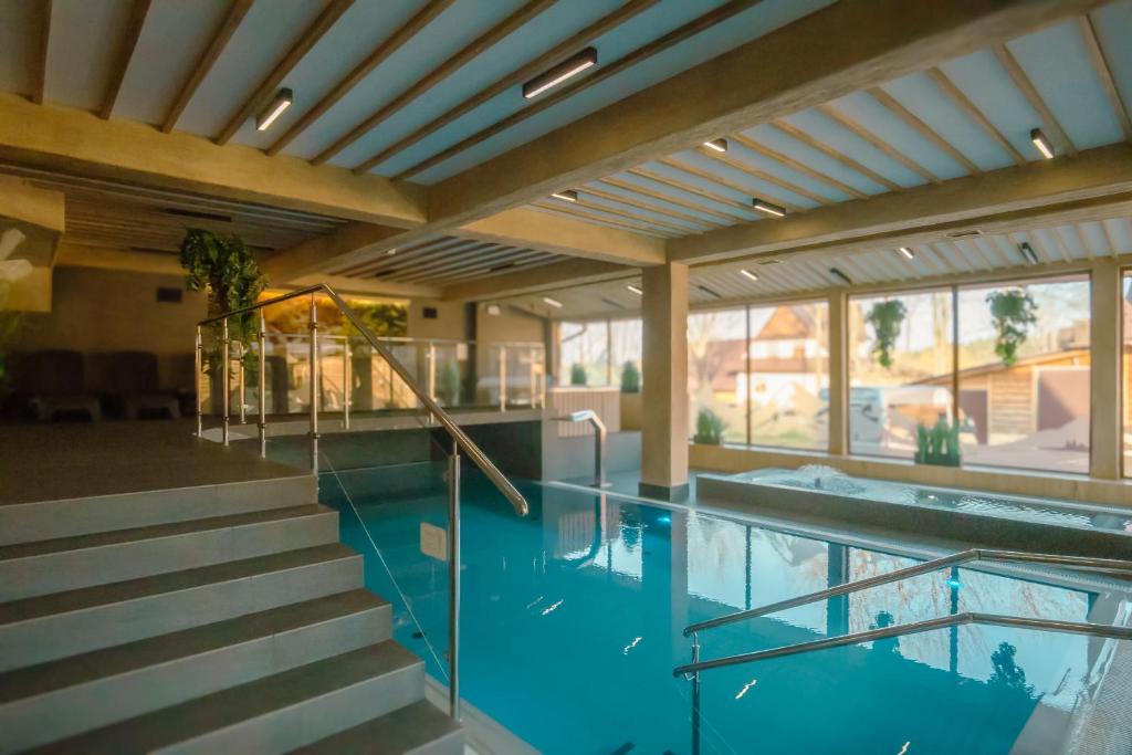 a swimming pool in a house with stairs and windows at Helan Family & SPA in Zakopane