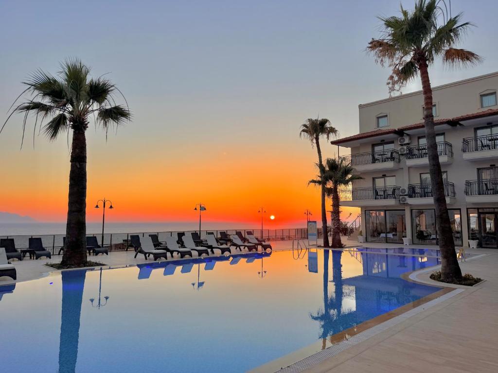 a swimming pool with palm trees and a hotel at Altamare Hotel in Kuşadası